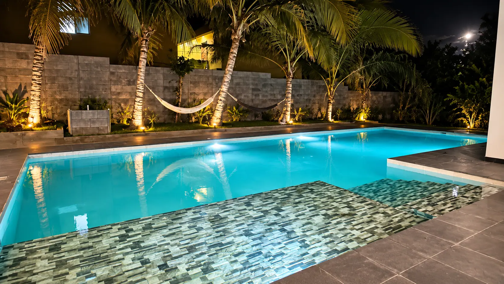 Piscina iluminada de noche entre palmeras en Coco Beach, Guatemala