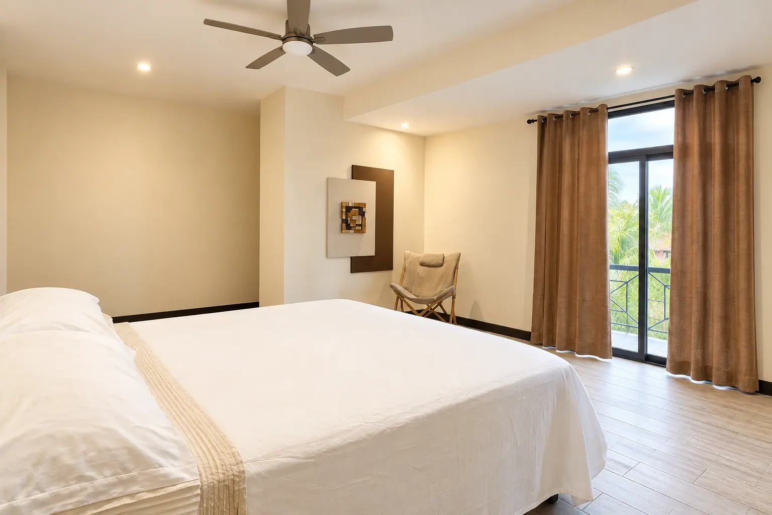 Suite de Coco Beach con cama de matrimonio, ventilador de techo y balcón a las palmeras