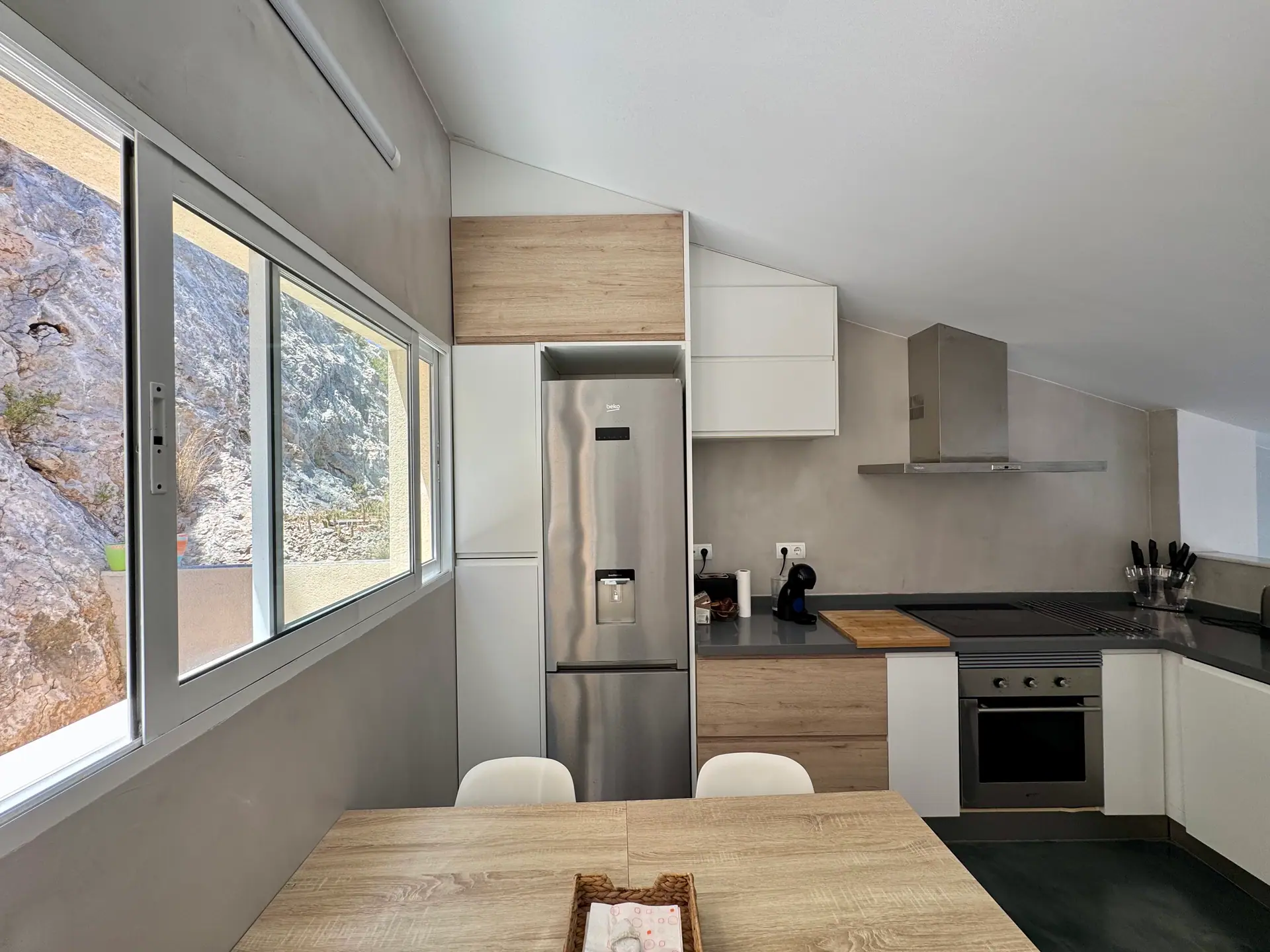 Cocina abierta de Villa Cap Blanc con ventanal a la roca del acantilado